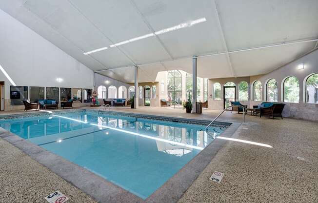 Indoor pool with high ceiling and patio seating