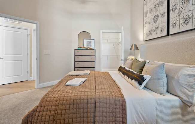 A bedroom with a bed, nightstand, and a dresser with a mirror.