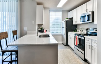 an open kitchen with white cabinets and black appliances and a white counter top