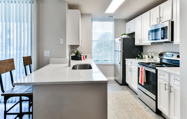 an open kitchen with white cabinets and black appliances and a white counter top