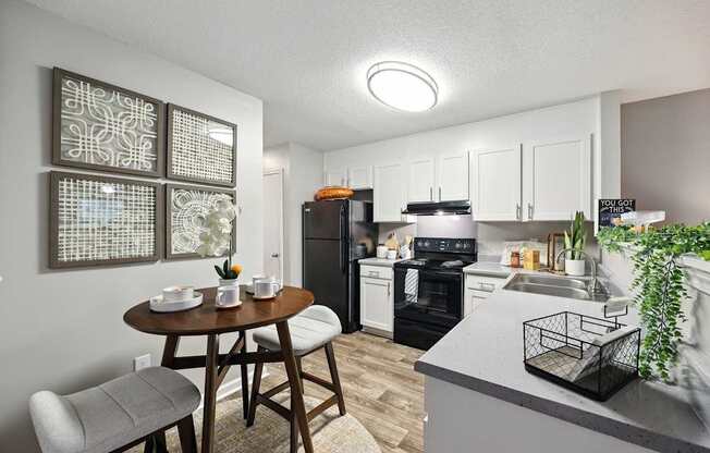 A kitchen with a table and chairs in the foreground and a countertop with a plant on it in the background.