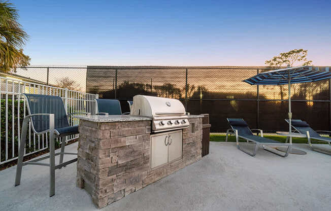 Outdoor BBQ Area with Lounge Furniture at Arbors at Orange Park Apartments located in Orange Park, FL.