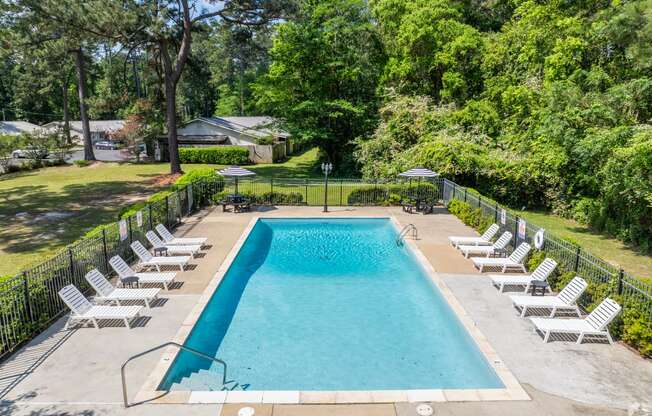 a swimming pool with white chairs and a fence around it