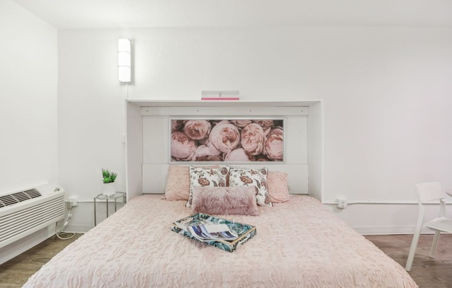 a bedroom with a bed and a painting of roses on the wall