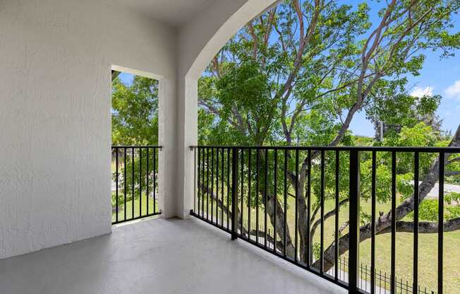 A balcony with a black railing and a view of trees.