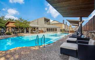 A large outdoor swimming pool with lounge chairs and a building in the background.