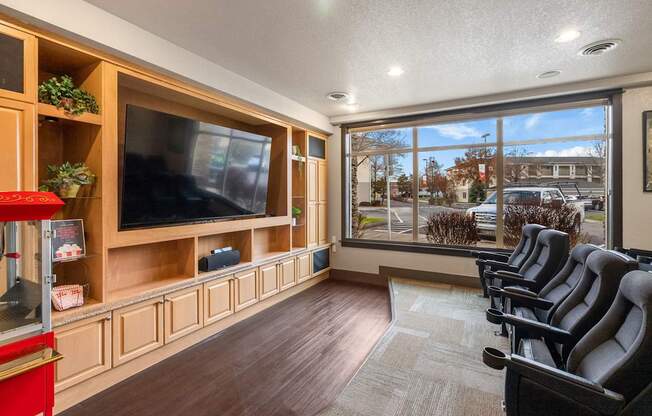 A room with a row of chairs and a television.