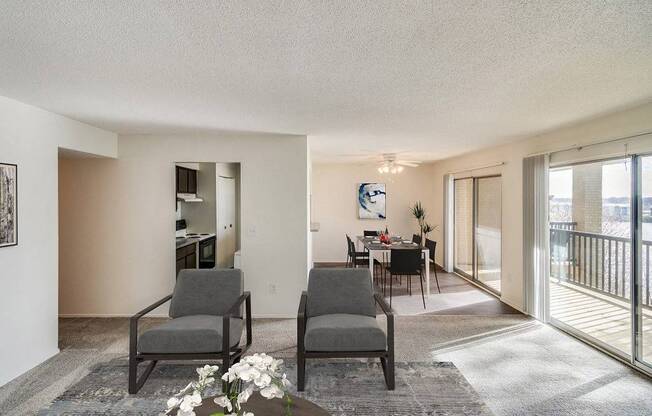 Two grey chairs are placed in a room with a table and a vase of flowers.