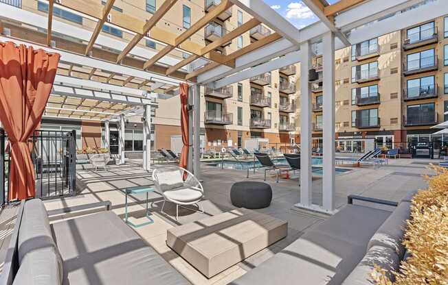 A patio with a white pergola and orange curtains.
