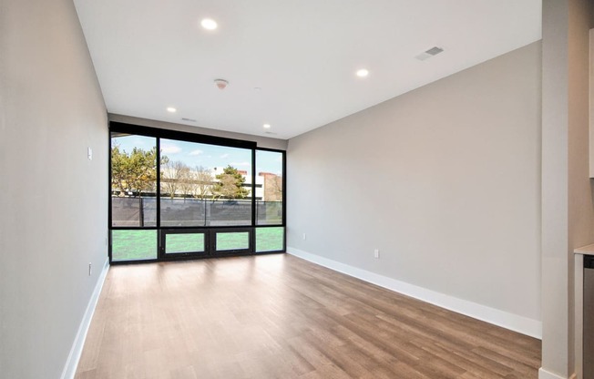 the living room of a new home with a large window and wooden floors
