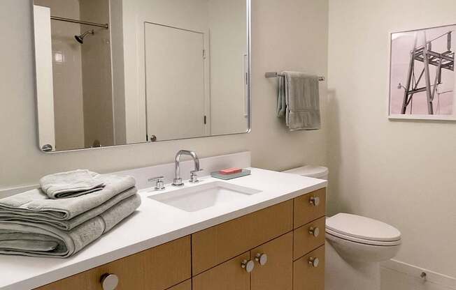 A bathroom with a toilet, sink, and mirror.