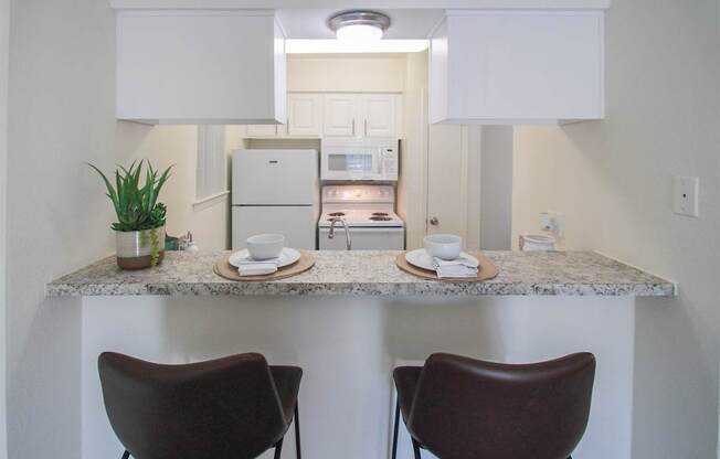 This is a photo of the breakfast bar and kitchen in the 558 square foot 1 bedroom, 1 bath model apartment at The Summit at Midtown Apartments in Dallas, TX.
