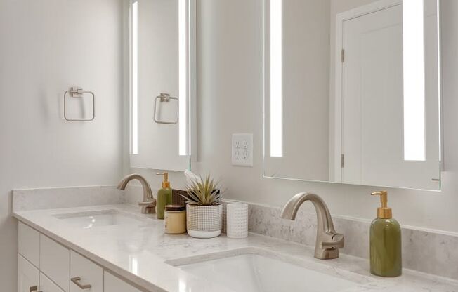 a white bathroom with two mirrors and two sinks