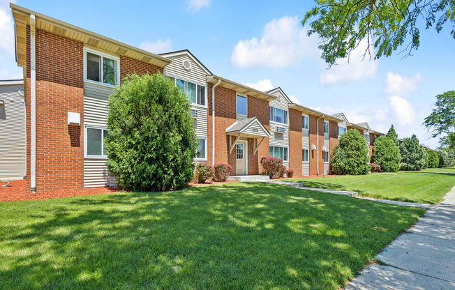 a row of brick apartment buildings with green grass and trees