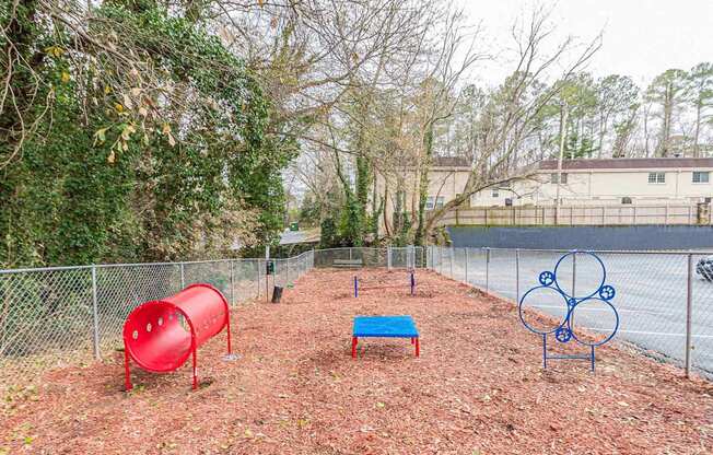 A playground with a red slide, a blue bench, and a blue metal structure.