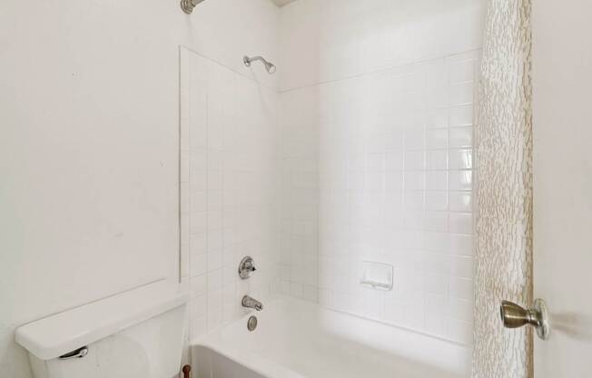 A white bathroom with a tub, toilet and sink.