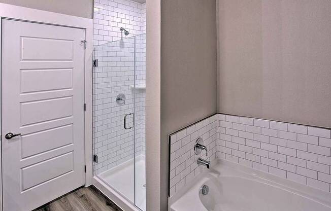 a bathroom with a tub and a shower and a door at Hunters Creek Apartments, Denton, 76210