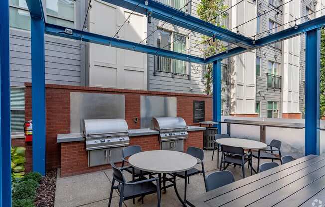 a patio with tables and barbecue grills and tables and chairs