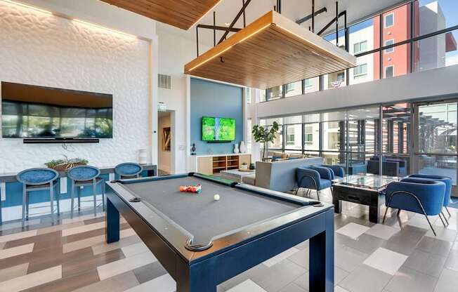 A pool table is in the middle of a room with blue chairs.