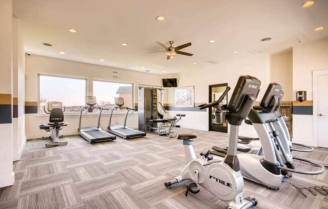 A gym with a variety of exercise equipment including treadmills, stationary bikes, and elliptical machines at Mountain Vista Apartments, Lakewood, 80228