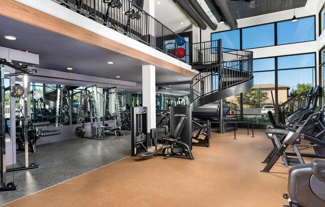 A spacious two-level fitness center at Modera Higley Commons, featuring expansive windows, advanced equipment, and room to train at your own pace.