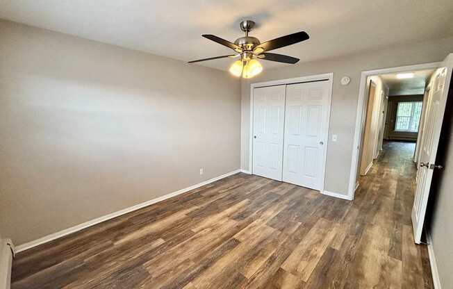 A room with a ceiling fan and wood flooring.
