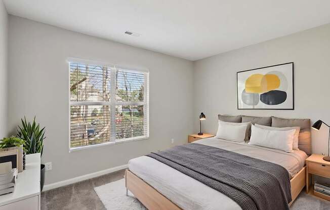 A bedroom with a large bed and a painting on the wall.