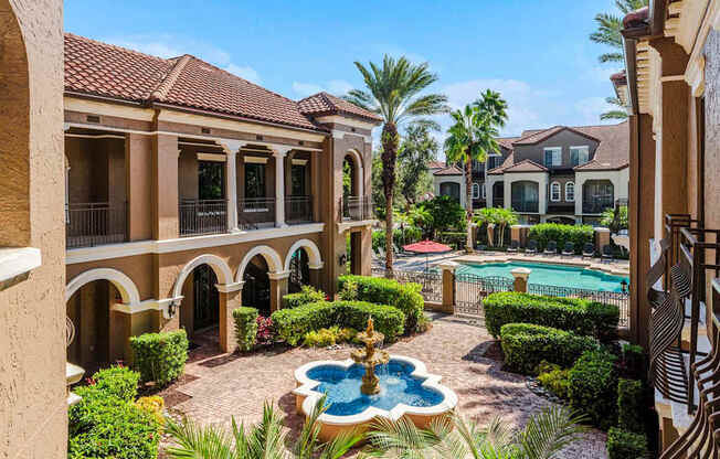 Courtyard fountain leading to the resort-style pool and palm-lined architecture.