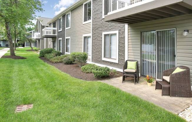 a grassy area with two chairs and a tree in the background