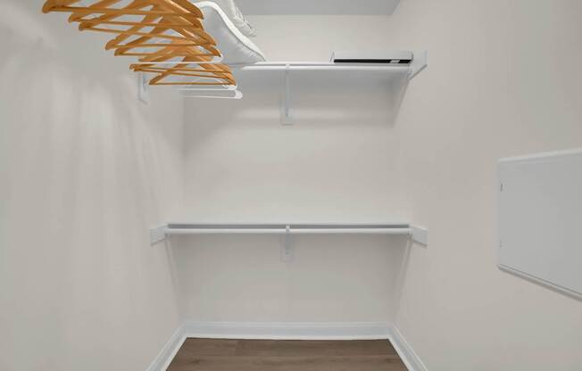 A white closet with a shelf and a hanger rack.
