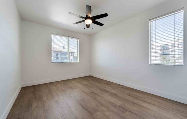 an empty living room with wood floors and a ceiling fan