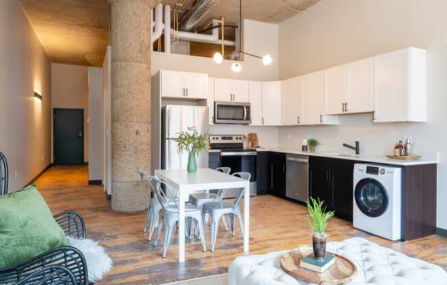 a living room with a white table and chairs and a kitchen with black and white appliances at The Draper, Missouri