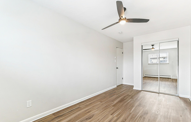 Bright, airy bedroom with sleek floors and mirrored closet doors, perfect for modern living.
