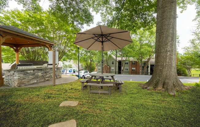 a picnic table with an umbrella next to a tree