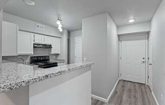 A kitchen with a granite countertop and white cabinets.