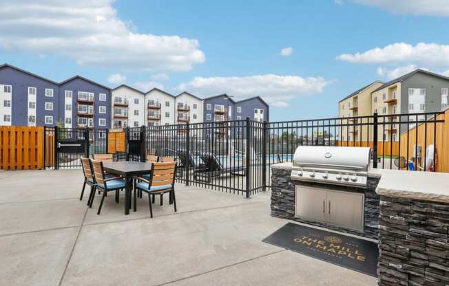 a patio with a grill and a table and chairs