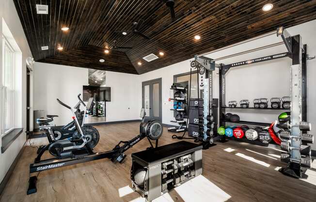 a home gym with exercise machines and weights on a wooden floor