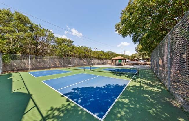 a pickleball court with blue and green courts and a fence