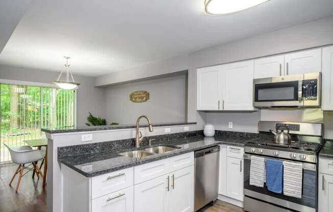 A kitchen with white cabinets and a black countertop.