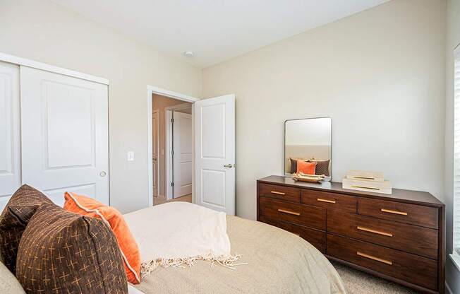 A bedroom with a bed, dresser, and mirror.