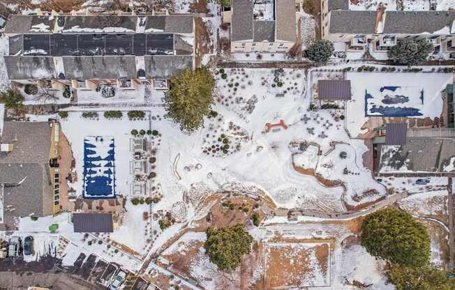 A snow-covered landscape with a swimming pool and a building.