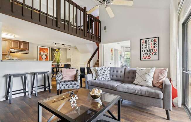 A living room with a grey couch and a glass coffee table.