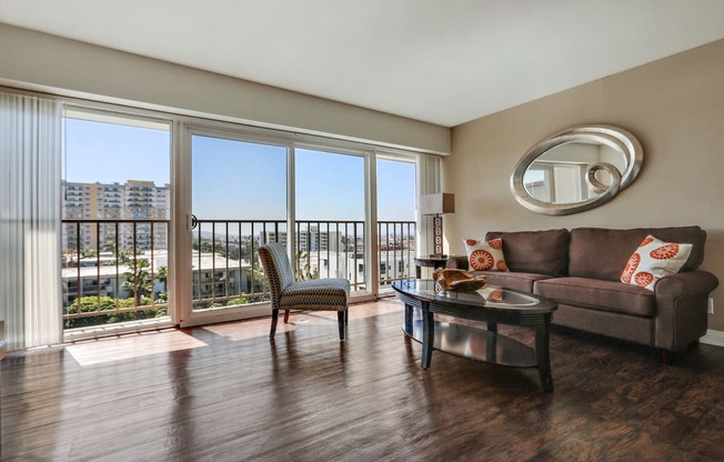 Living room with wood style floors, large balcony on the left, large windows with great views