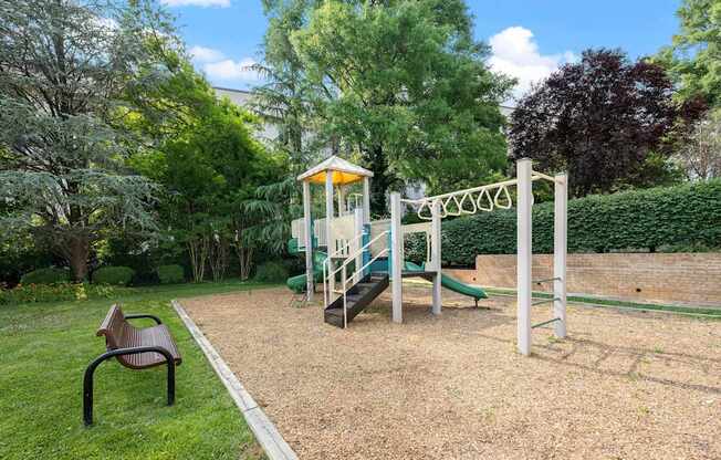A playground with a slide, swing set, and a bench.