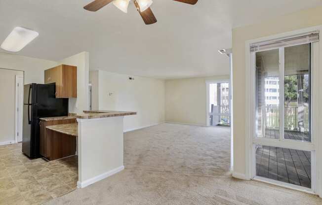 an empty living room and kitchen with a door to a balcony