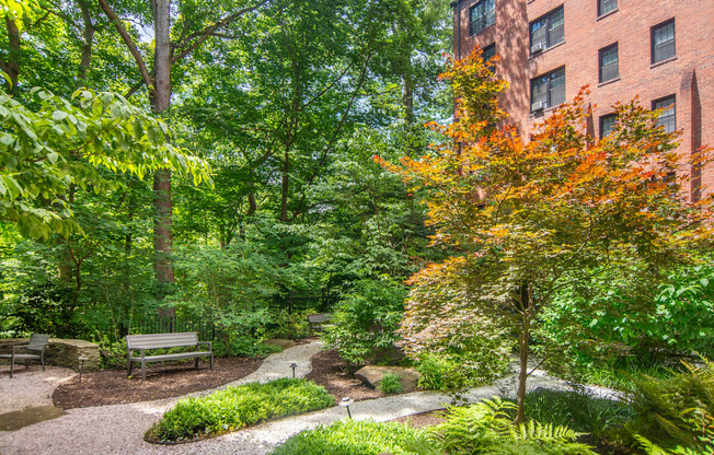 a park with benches and trees in front of a brick building