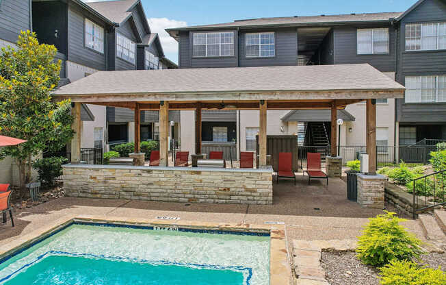 A pool in a backyard with a patio and chairs.