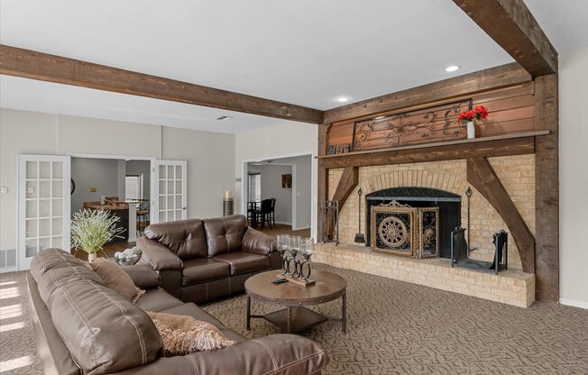 A living room with a brown leather couch and a fireplace.