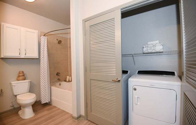 A white toilet sits in a bathroom next to a white cabinet.