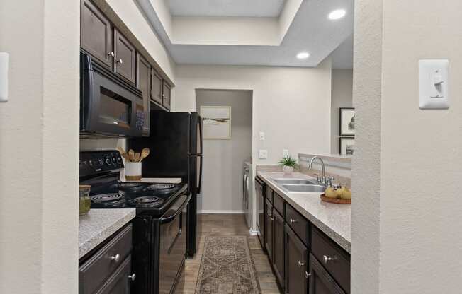 view of kitchen with black appliances and counter tops with sink and black refrigerator and stove